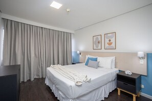 A hotel room with a bed, bedside tables, a desk, curtains, and two wall-mounted artworks. - Suite na Berrini by Conviva (São Paulo)