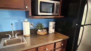 Une cuisine équipée d’un évier en acier inoxydable, d’un four à micro-ondes, d’une machine à café et d’un réfrigérateur.