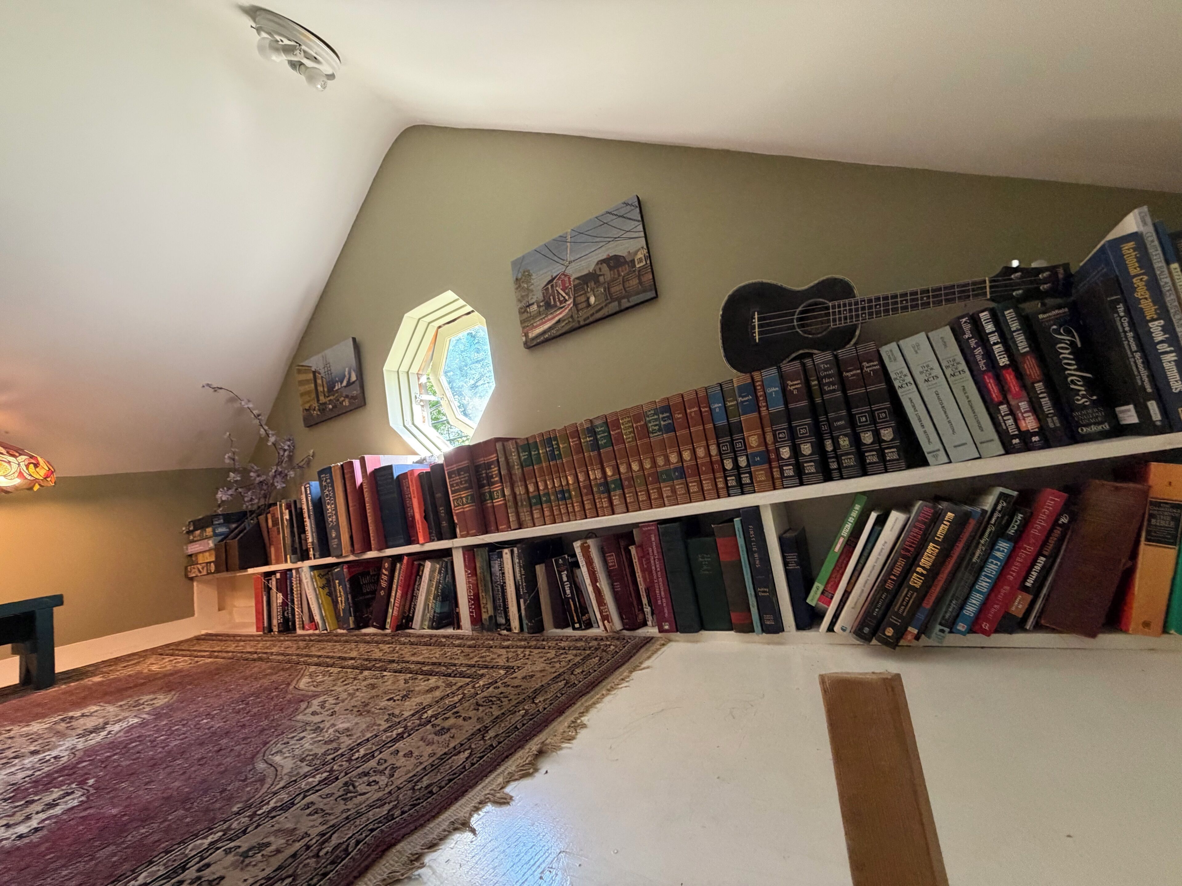 A library with bookshelves, a guitar, and a hexagonal window.