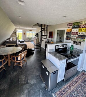 Una cocina amplia con encimeras de granito, un refrigerador de acero inoxidable y un horno negro.