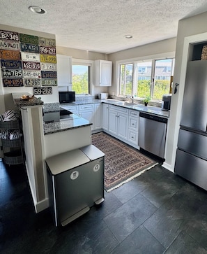 A modern kitchen with white cabinetry, a stainless steel refrigerator, and a built-in dishwasher.