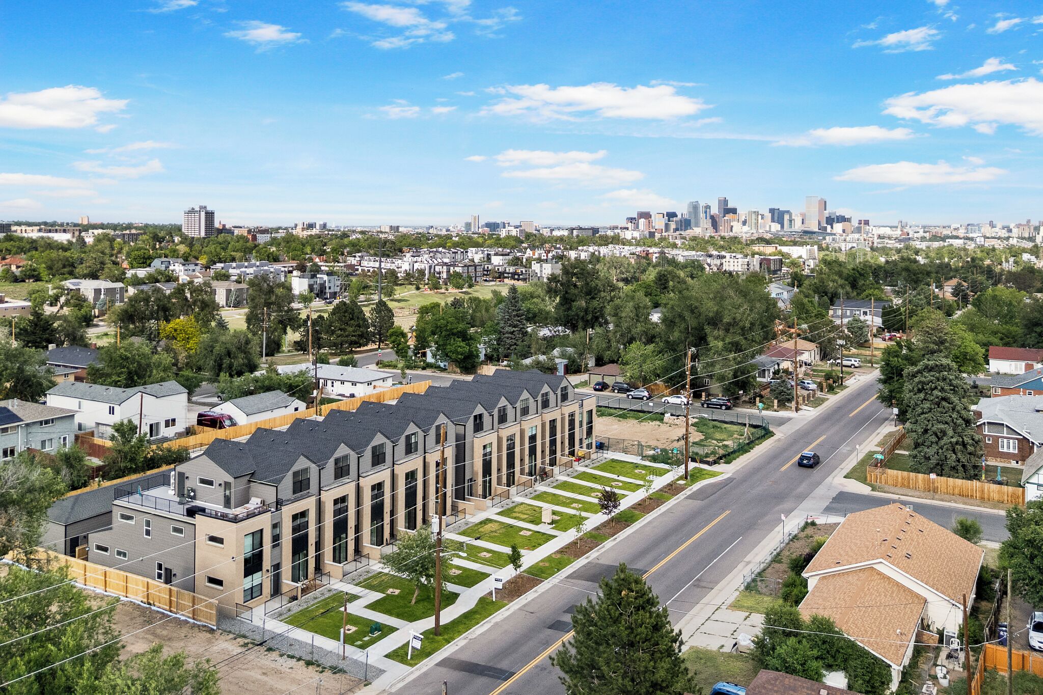 A residential area with modern apartment buildings, a main road, and a distant city skyline.