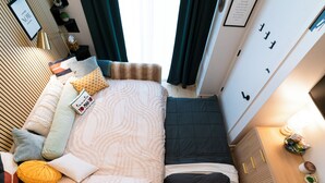 Une chambre d’hôtel de taille réduite, comprenant un lit, une table de chevet et une petite fenêtre.