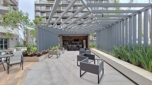 An outdoor patio area with seating, a kitchen, and a view of a residential building. - Nex One Vila Nova (São Paulo)