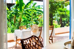 An outdoor dining area with a table, chairs, and a view of lush greenery. - Andorinha OCV | Peaceful Retreat, Pool & Garden (Albufeira)