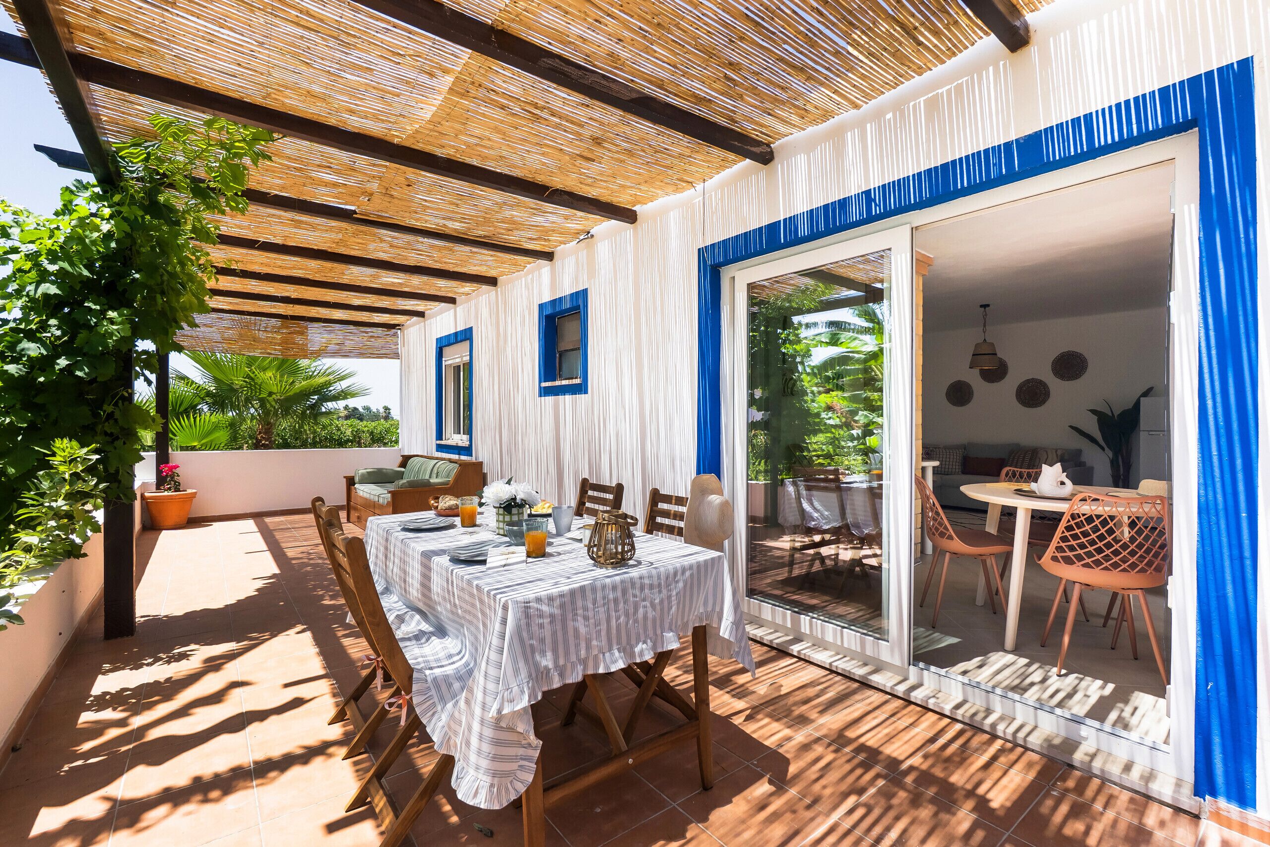 An outdoor patio with a table and chairs, a pergola, and a view of the garden.