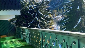 Uma varanda com vista para montanhas cobertas de neve e árvores perenes.