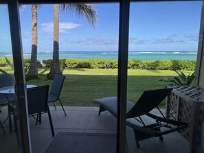 Eine Terrasse mit Meerblick, eine Rasenfläche und ein Tisch mit Stühlen.