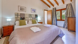 A bedroom with a bed, bedside tables, a wooden headboard, a window with curtains, and a wooden wardrobe. - Villa rental in Moraira PONENT (Moraira)