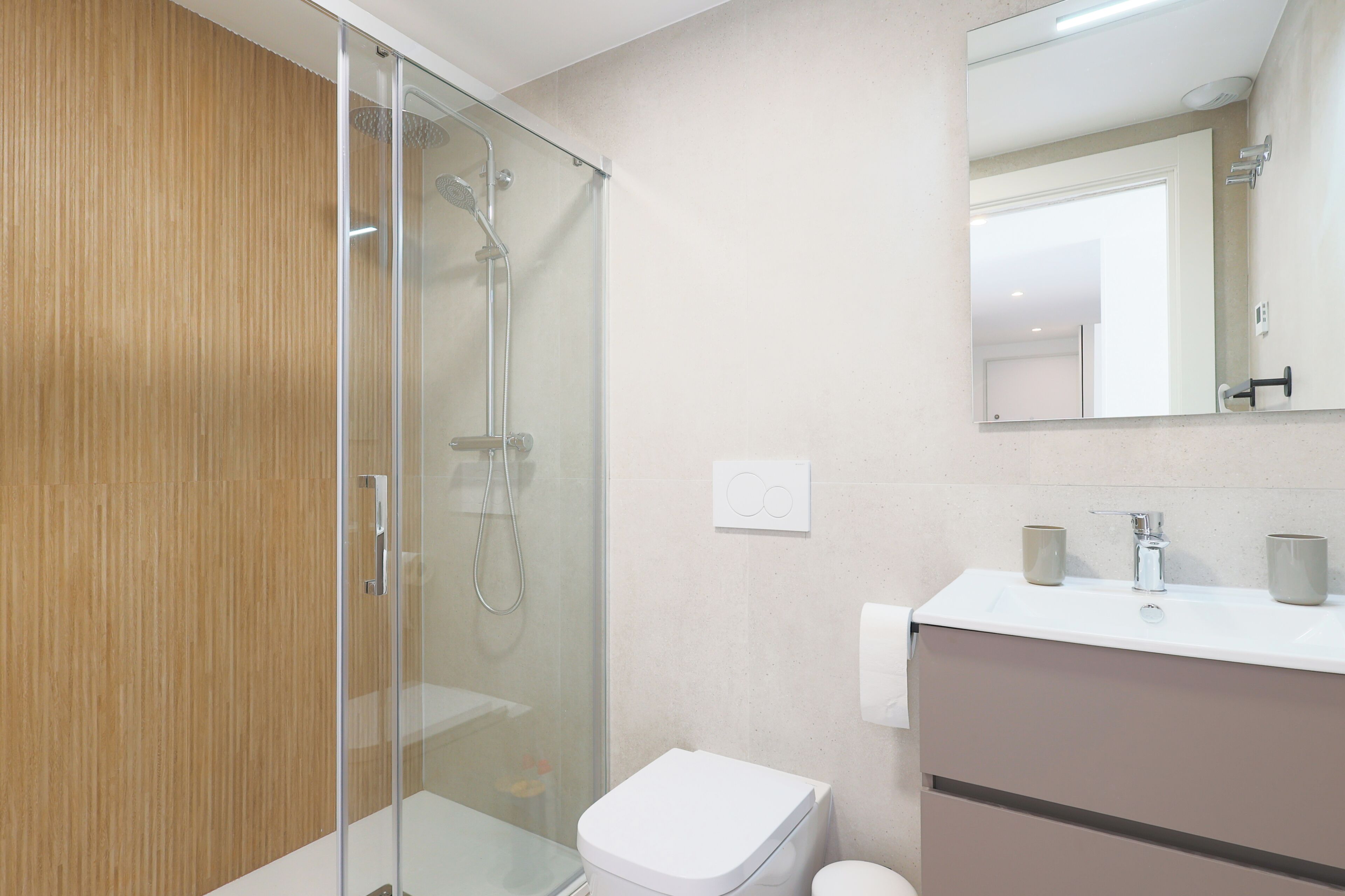 Une salle de bain moderne avec une douche à parois de verre, des toilettes et un lavabo avec un miroir au-dessus.