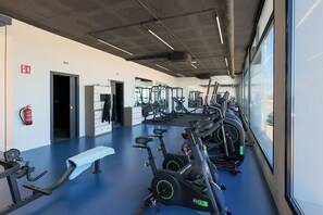 Ein Fitnessraum mit Trainingsgeräten, einer Bank und einem Feuerlöscher.