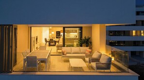 A modern outdoor living space with a dining area, seating, and a view of the interior. - Brand new 3 bedroom appartement at Santa Rosalia Lake & Life Resort (MC)