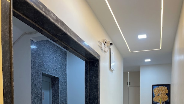 A hallway with a marble floor, a black marble column, and a door leading to a room. - Hotel Legacy Inn (Nagpur)