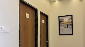 A hallway with two wooden doors labeled '101' and '102', a framed picture on the wall, and a light switch on the left. - Hotel Legacy Inn (Nagpur)