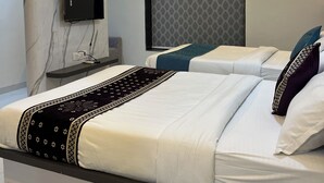 A modern hotel room with a marble wall, a flat-screen TV, two beds with white bedding, a ceiling fan, and an air conditioning unit. - Hotel Legacy Inn (Nagpur)