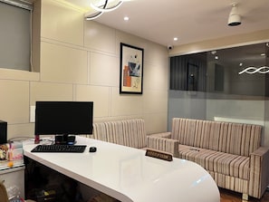 A reception desk with a computer, a keyboard, and a mouse. There are striped sofas and a framed picture on the wall. - Hotel Legacy Inn (Nagpur)