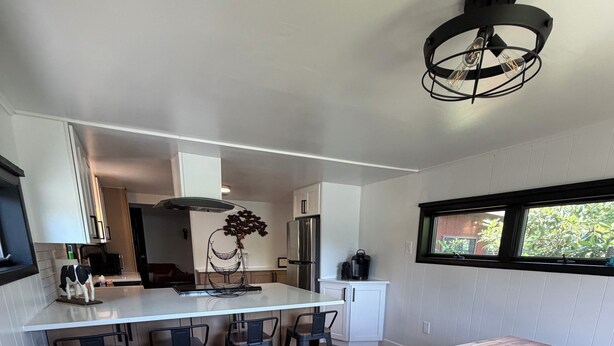 Uma cozinha moderna com ilha de madeira, banquetas, eletrodomésticos de aço inoxidável e uma janela com vista.