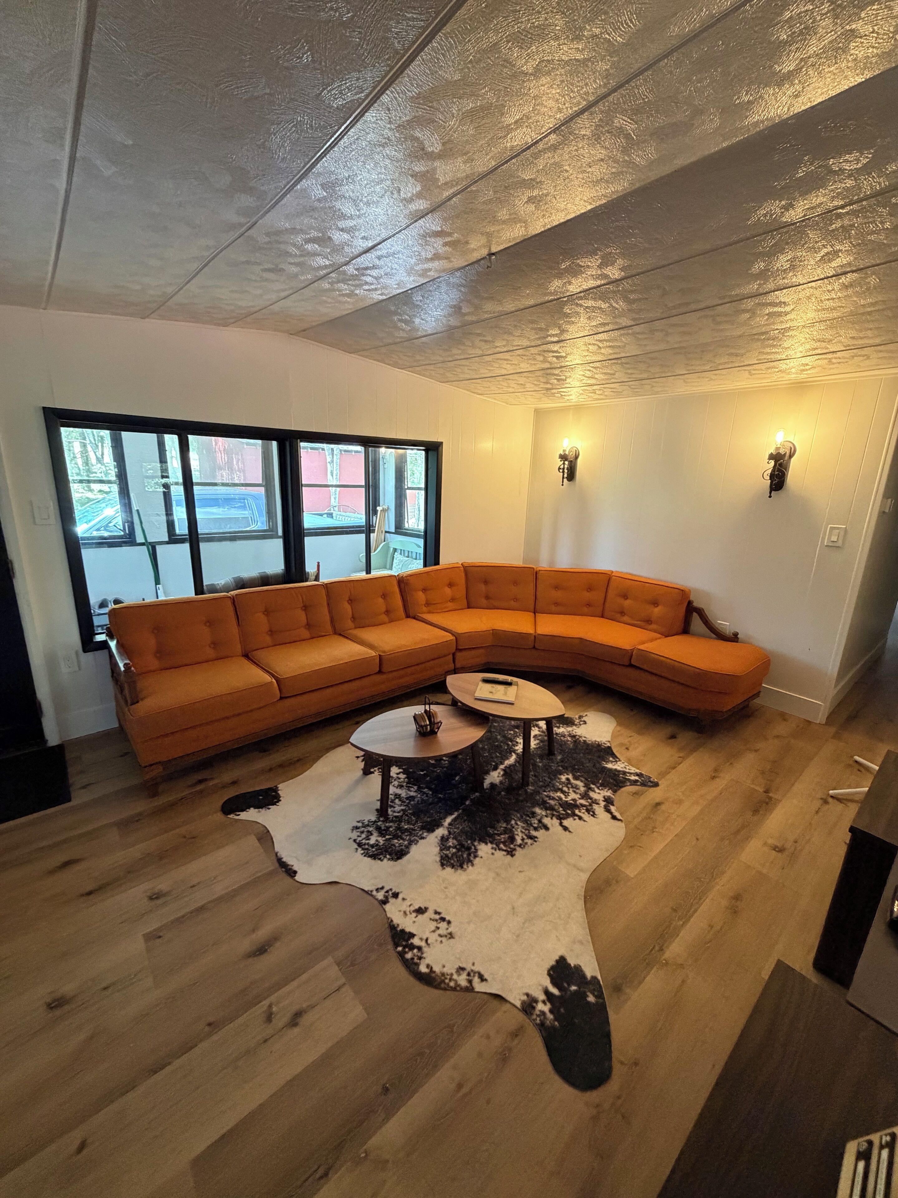 A modern living room with a large L-shaped orange sofa, a round coffee table, and a cowhide rug.