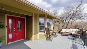 A wooden deck with a red door, a covered porch, and outdoor furniture. - Fabulous 5-bedroom house in Colorado Springs, perfect for relaxing (Colorado Springs)