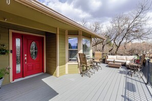 A wooden deck with a red door, a covered porch, and outdoor furniture. - Fabulous 5-bedroom house in Colorado Springs, perfect for relaxing (Colorado Springs)