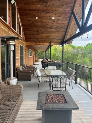 Un patio exterior cubierto con mobiliario de mimbre, una mesa y una chimenea.
