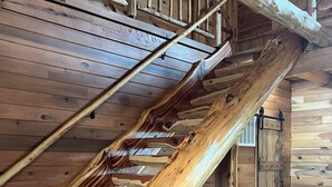 En trappe i træ med et rustikt design, træloft og en skraldespand i metal.