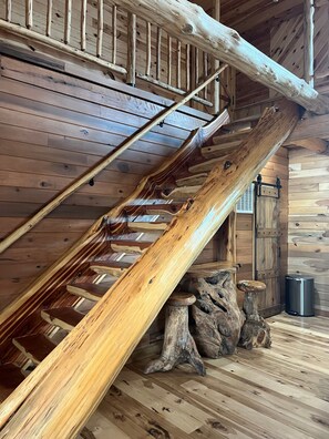 Eine hölzerne Treppe mit rustikalem Design, eine Holzzieldecke und ein Metallmülleimer.