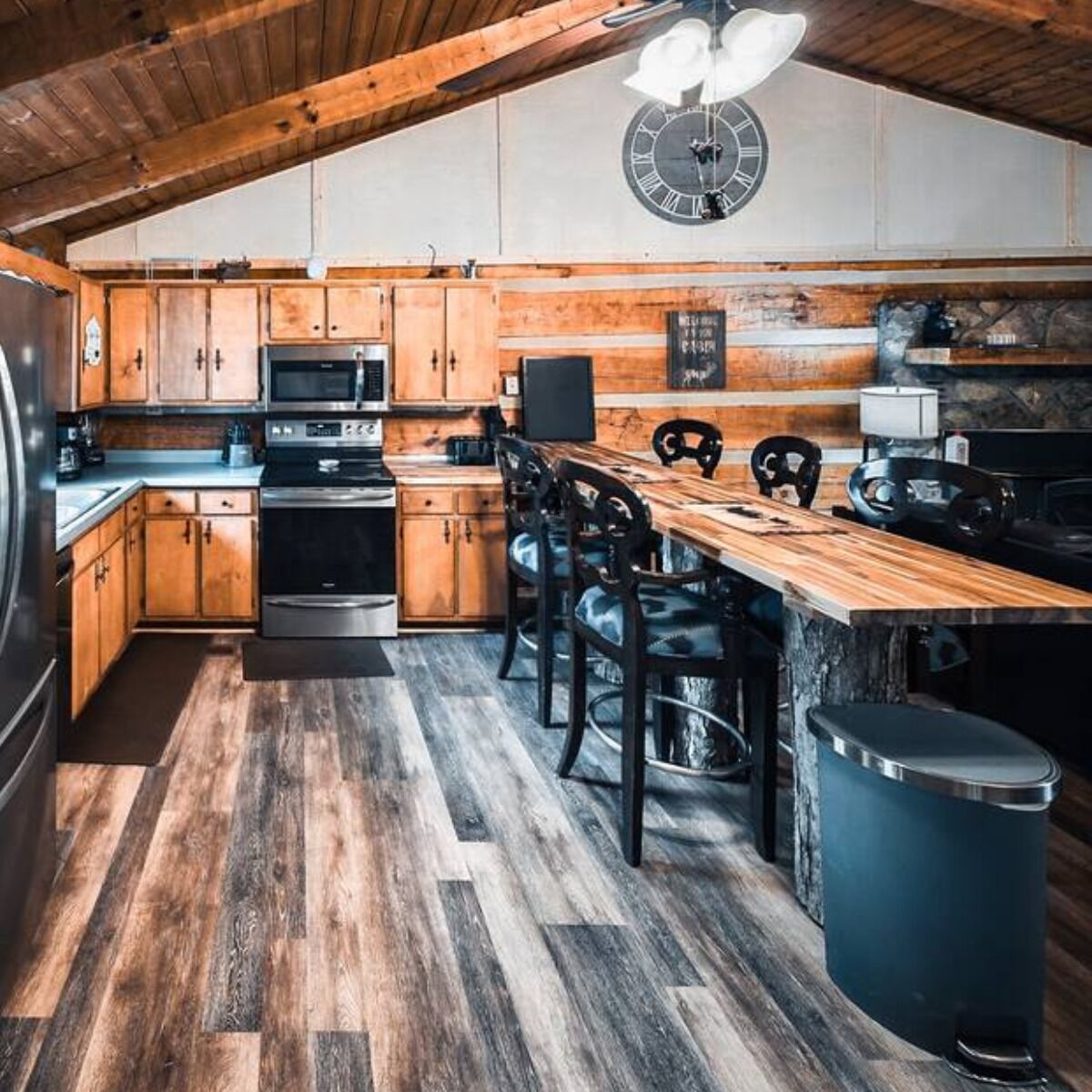 A kitchen with wooden cabinets, a wooden dining table, and a clock on the wall.