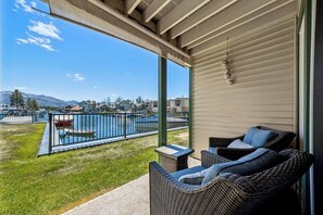 Ein Balkon mit Korbmöbeln, Blick auf einen Swimmingpool und einem Bergpanorama.