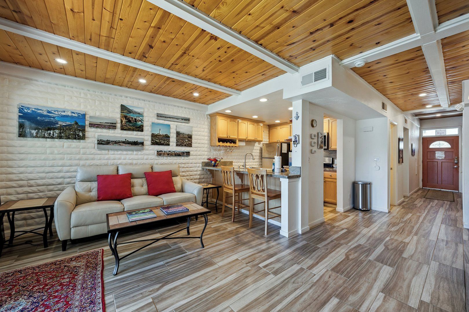 A cozy living room with a sofa, coffee table, and a rug. There is a kitchen area with wooden cabinets and a dining space.
