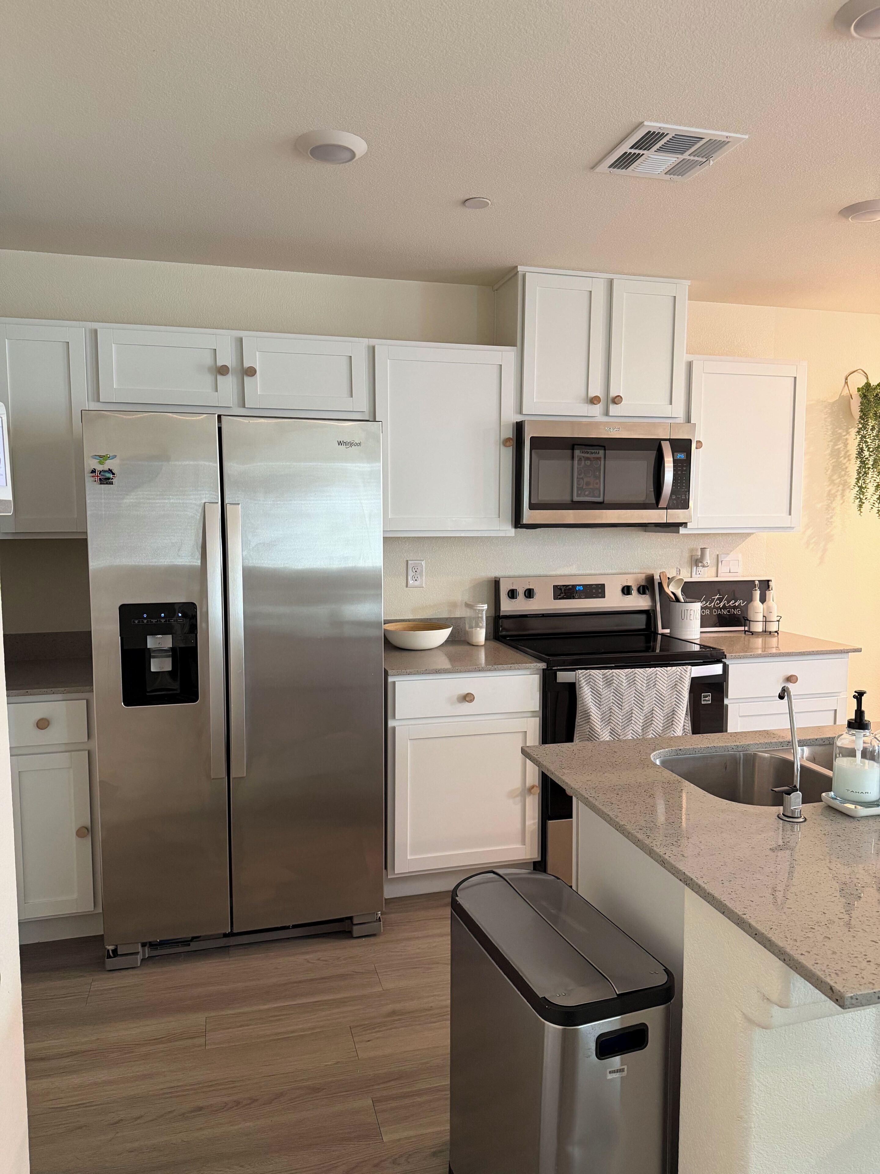 A modern kitchen with stainless steel appliances, white cabinetry, and a built-in microwave.