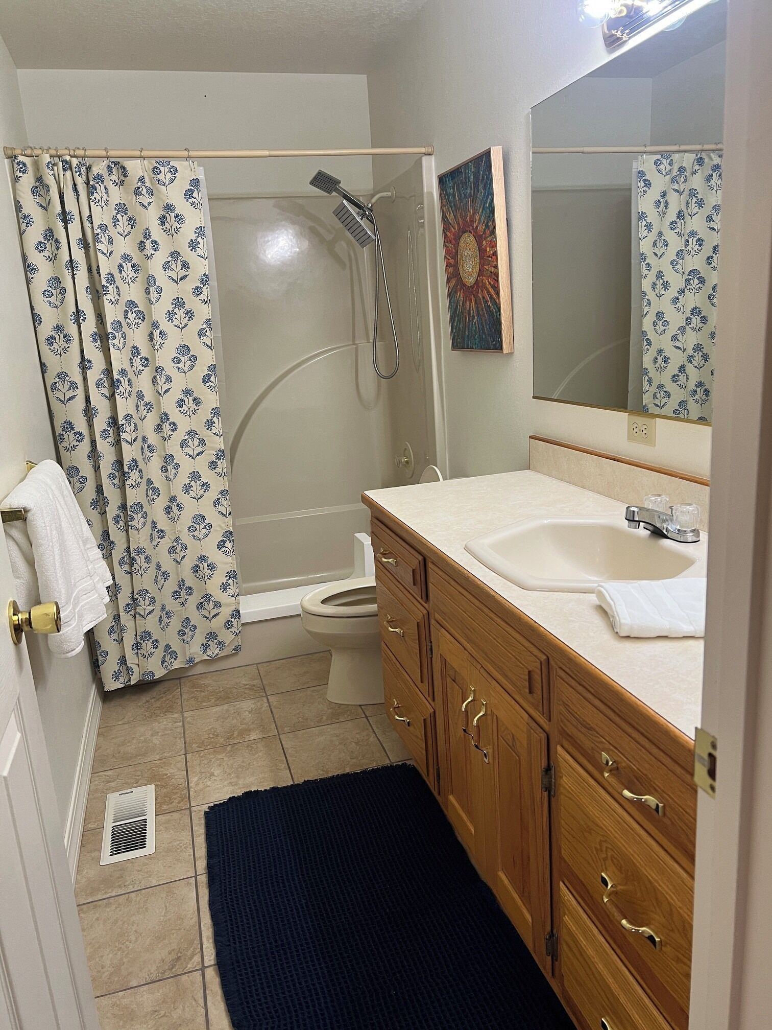 A bathroom with a shower, toilet, sink, and wooden cabinets.