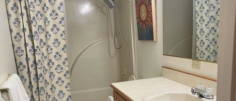 A bathroom with a shower, toilet, sink, and wooden cabinets.