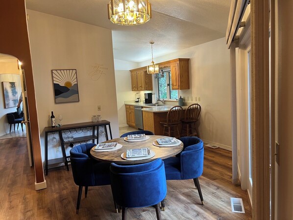 A dining area with a round table, blue upholstered chairs, and a chandelier.