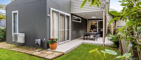 A modern two-story house with a patio, a large window, and an air conditioning unit.
