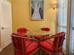 A room with a glass table surrounded by four red chairs, a painting on the wall, and a door with a window. - Comfortable Caribbean getaway with all that you need (Christiansted)