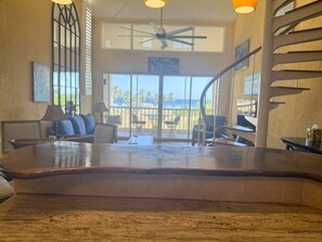 A spacious indoor area with a curved wooden table, seating, and a view of the ocean through large windows. - Comfortable Caribbean getaway with all that you need (Christiansted)