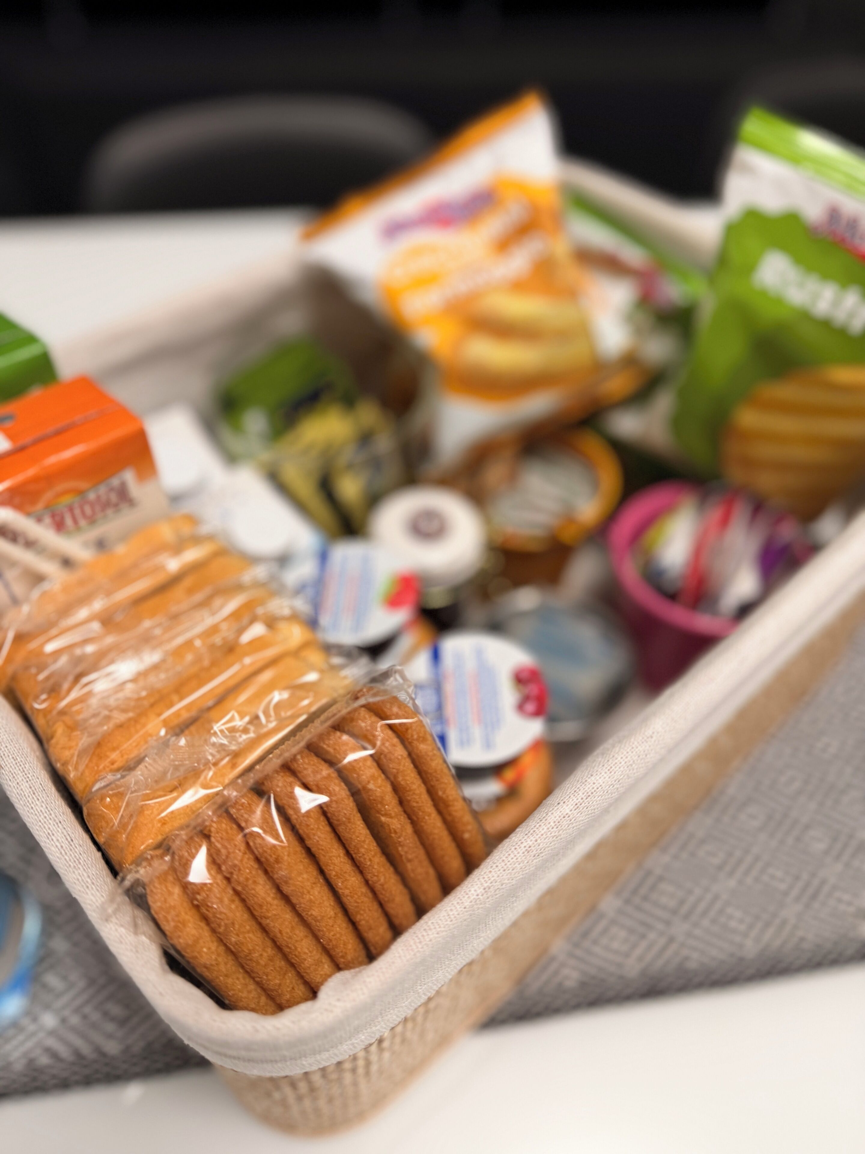A storage bin containing various food items including bread, packaged snacks, and a roll of tape.