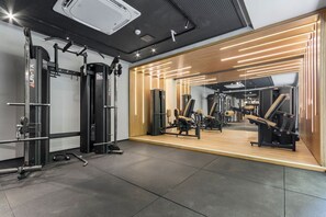 Ein Fitnessraum mit Gewichthebern, einer Spiegelwand und einer Wand mit Holzelementen.