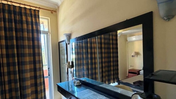 A hotel room with a desk, chair, and a coffee maker.