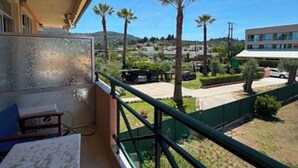 A balcony with a view of palm trees and a building in the distance.