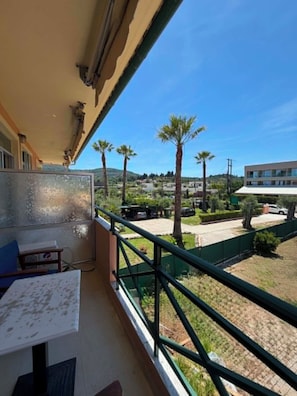 Un balcon avec vue sur des palmiers et un bâtiment situé au loin.