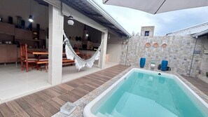 A swimming pool, a hammock, a dining area, and a stone wall with decorative plates.