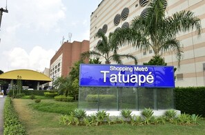 Placa indicando 'Shopping Metro Tatuapé' com um edifício moderno ao fundo.