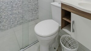 Un baño moderno con cabina de ducha de vidrio, inodoro y lavabo con encimera de madera.