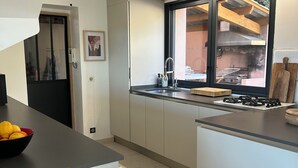 A modern kitchen with a large window, a built-in stove, and a sink. - Villa with a Pool Nestled in the Esterel Mountains, 10 Minutes from the Beaches of Mandelieu and Cannes (Fréjus)