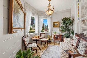 A room with a wooden floor, a chandelier, a sofa, a chair, a table with a chessboard, and a fan. - The Ultimate Historic Vibe: Queen Anne Victorian Meets Modern Indie Style Just Steps from The Courthouse Square (Prescott)