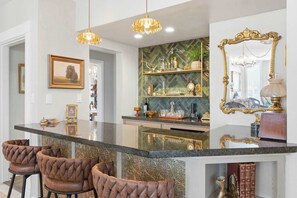 A kitchen with a marble countertop, pendant lights, a decorative mirror, and a hutch with glassware. - The Ultimate Historic Vibe: Queen Anne Victorian Meets Modern Indie Style Just Steps from The Courthouse Square (Prescott)