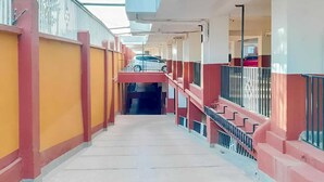 Un pasillo con escalera, barandales y una zona cubierta con vistas al exterior.