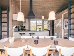Une cuisine moderne avec des murs en bois, un îlot central, des tabourets de bar et des luminaires suspendus.